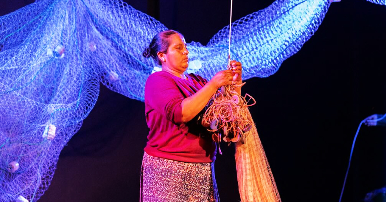 Una de las actrices de la obra Colando agua manipula una red de pesca en el escenario.